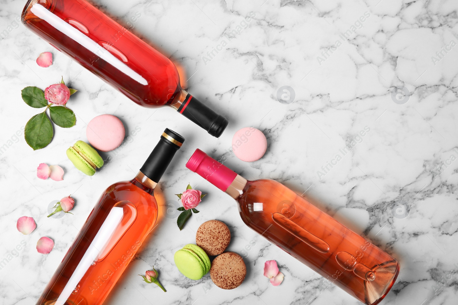 Photo of Flat lay composition with bottles of delicious rose wine on white marble table. Space for text