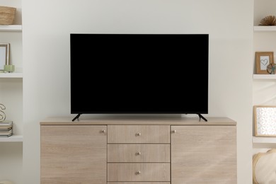 Photo of Stylish wide TV set on wooden cabinet in room