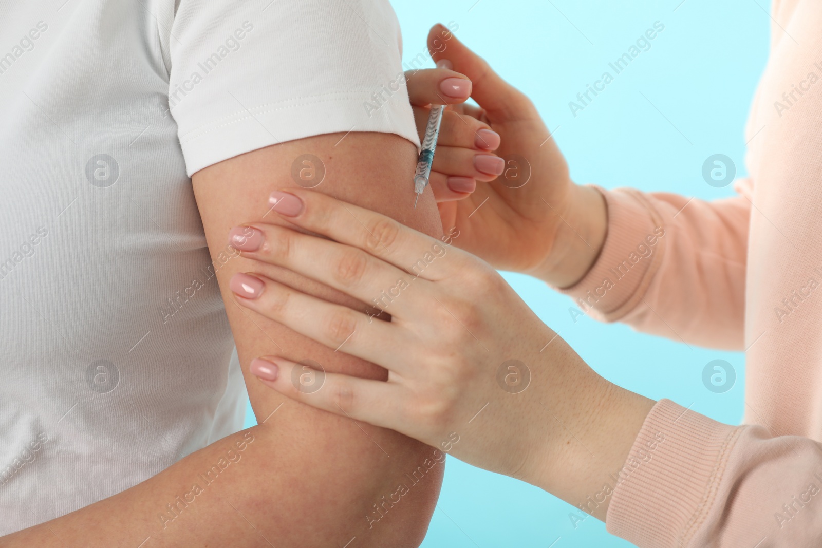 Photo of Diabetes. Woman getting insulin injection on light blue background, closeup