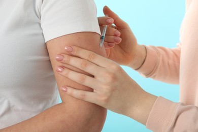 Diabetes. Woman getting insulin injection on light blue background, closeup