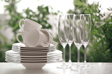 Photo of Setclean dishware and champagne glasses on white table against blurred background