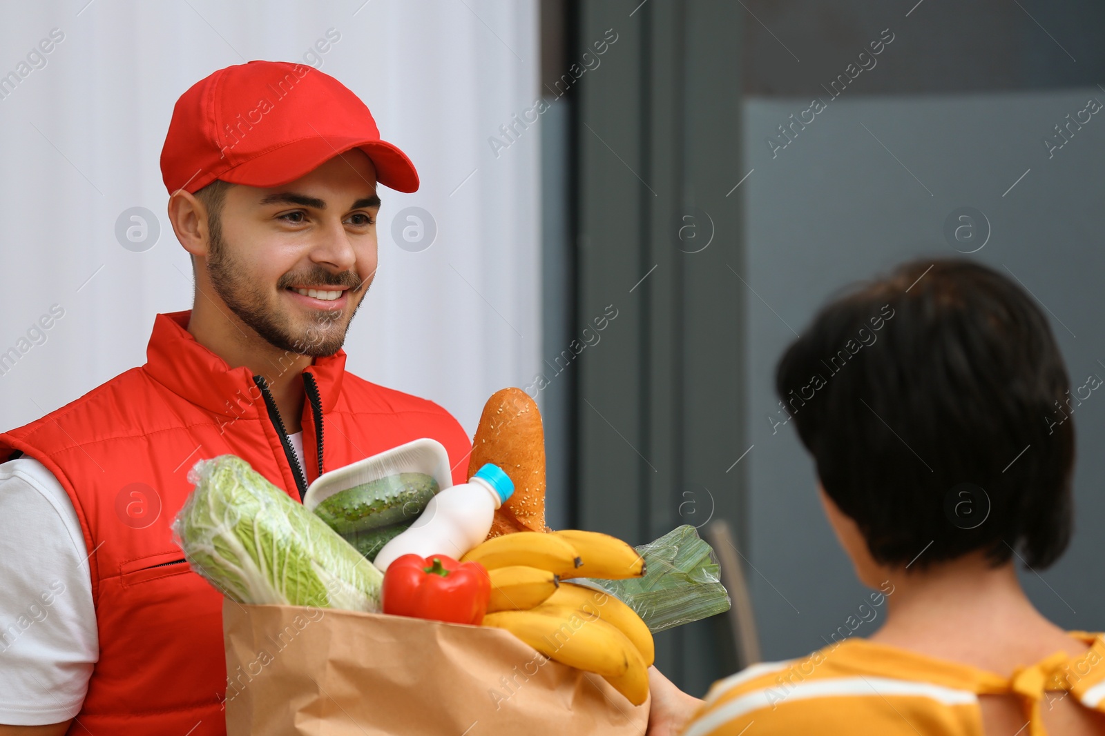 Photo of Male courier delivering food to client indoors