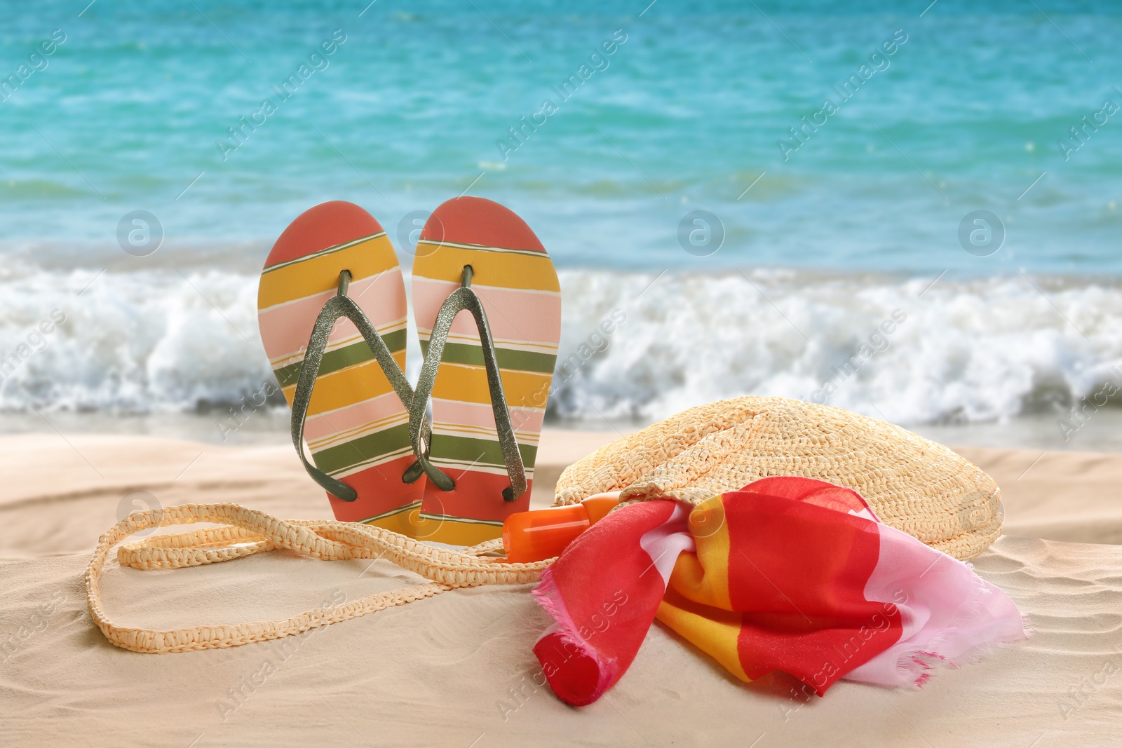 Image of Different beach accessories on sand near ocean