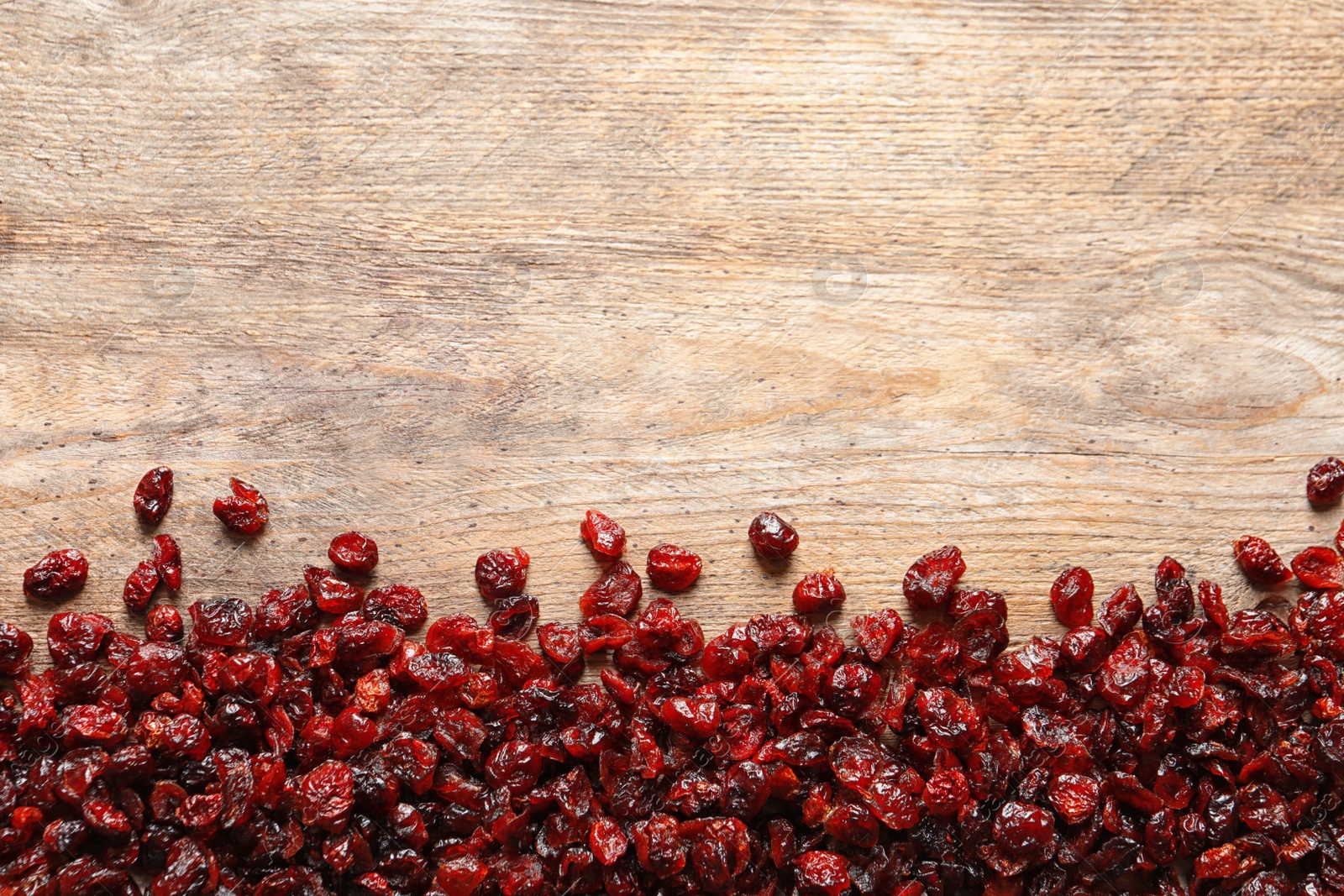 Photo of Tasty cranberries on wooden background, top view with space for text. Dried fruit as healthy snack