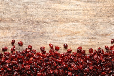 Photo of Tasty cranberries on wooden background, top view with space for text. Dried fruit as healthy snack