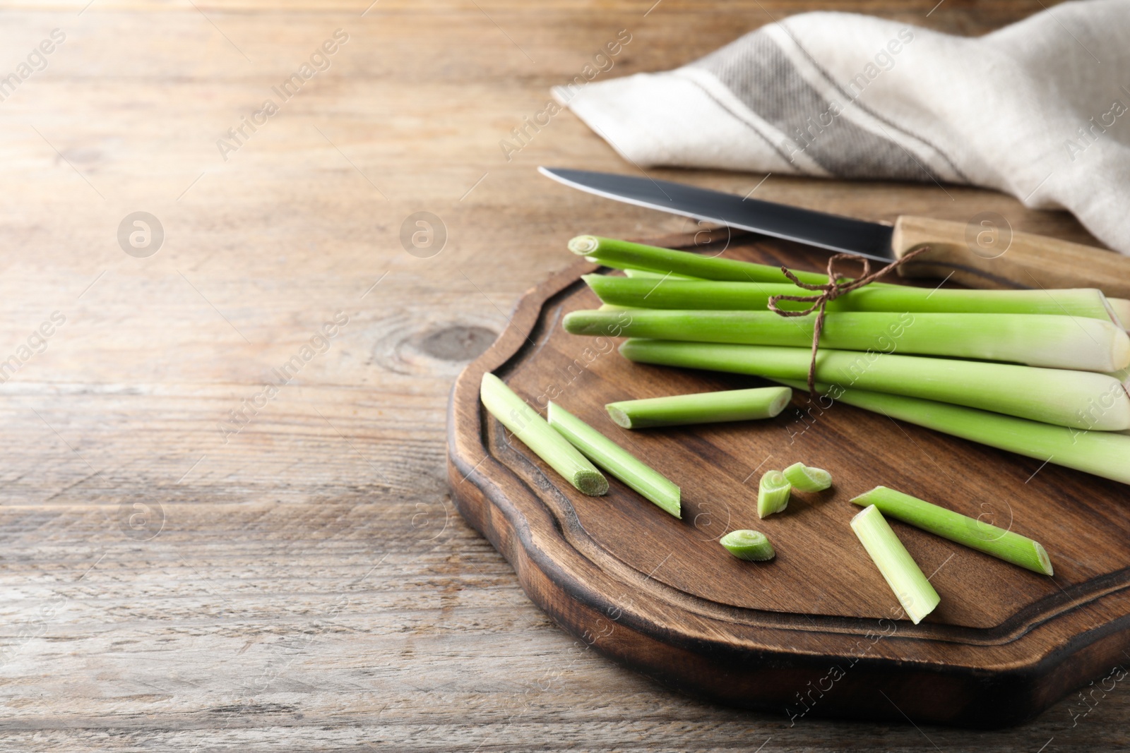 Photo of Fresh lemongrass, knife and cutting board on wooden table, space for text