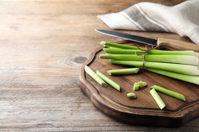 Photo of Fresh lemongrass, knife and cutting board on wooden table, space for text