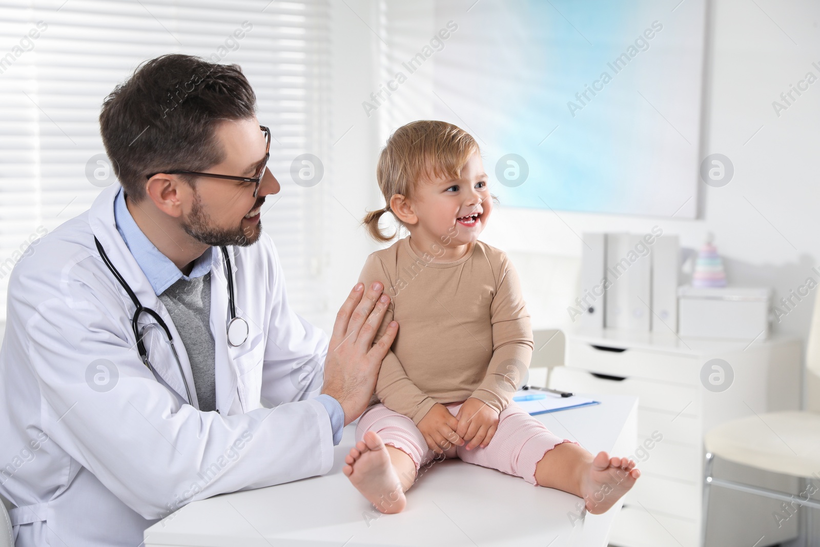 Photo of Pediatrician examining cute little baby in clinic