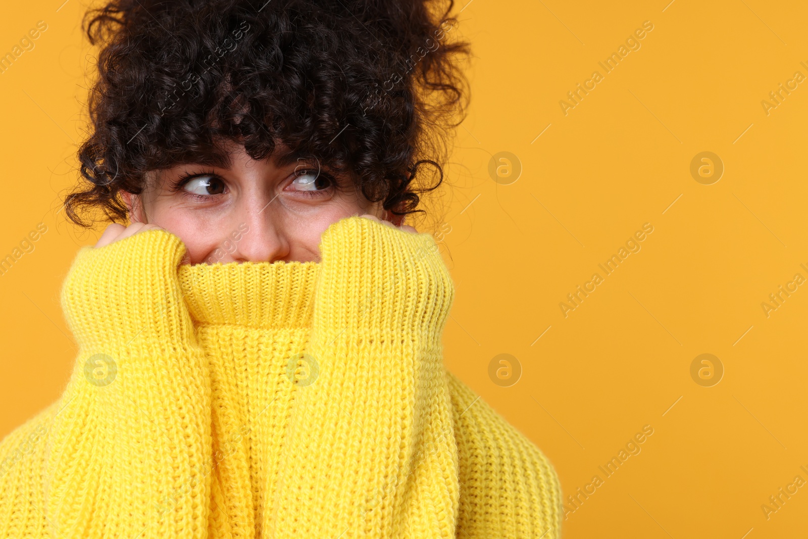 Photo of Young woman in stylish warm sweater on yellow background, space for text