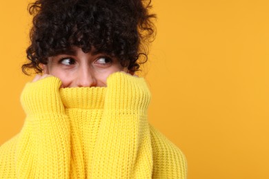 Young woman in stylish warm sweater on yellow background, space for text