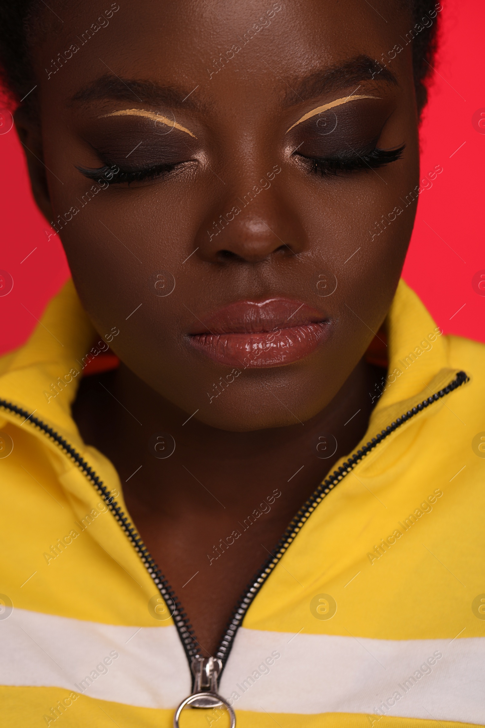 Photo of Fashionable portrait of beautiful woman with bright makeup on coral background, closeup