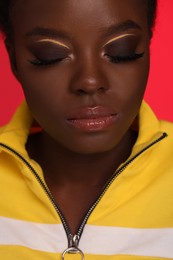 Photo of Fashionable portrait of beautiful woman with bright makeup on coral background, closeup