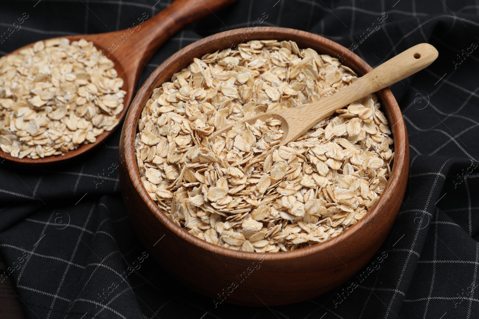 Photo of Bowl with scoop and spoon of oatmeal on table, closeup