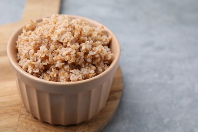 Tasty wheat porridge in bowl on grey table, closeup. Space for text