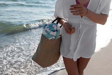 Woman carrying bag with beach towel near sea, closeup