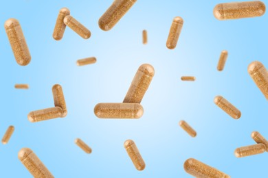 Image of Vitamin. Capsules falling on light blue gradient background