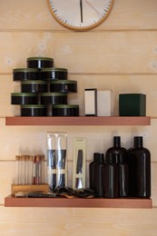 Photo of Shelves with professional hair cosmetics on wall in barbershop