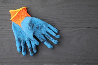 Pair of color gardening gloves on grey wooden table, top view. Space for text