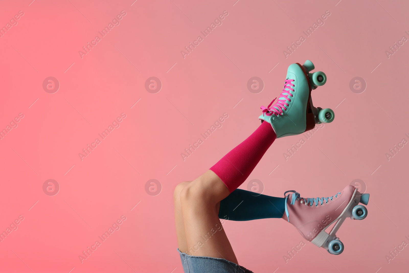 Photo of Woman with vintage roller skates on color background, closeup. Space for text