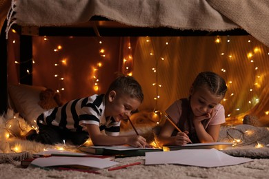 Children drawing in play tent at home