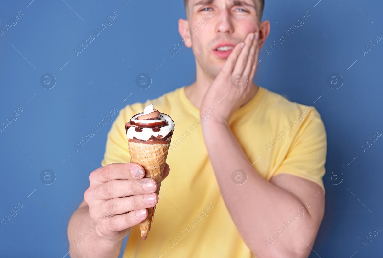 Photo of Young man with sensitive teeth and cold ice cream on color background