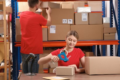 Post office worker packing parcel at counter indoors