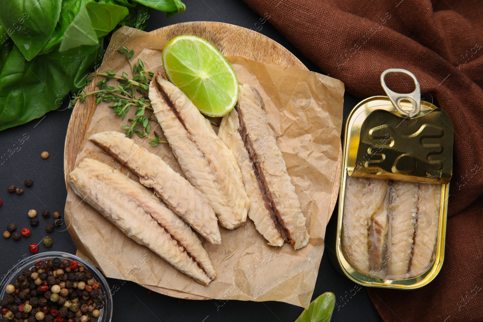 Photo of Canned mackerel fillets served on black table, flat lay