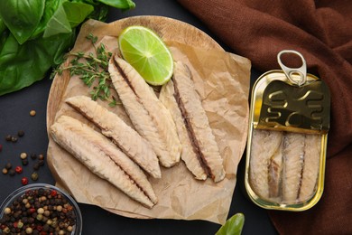 Photo of Canned mackerel fillets served on black table, flat lay