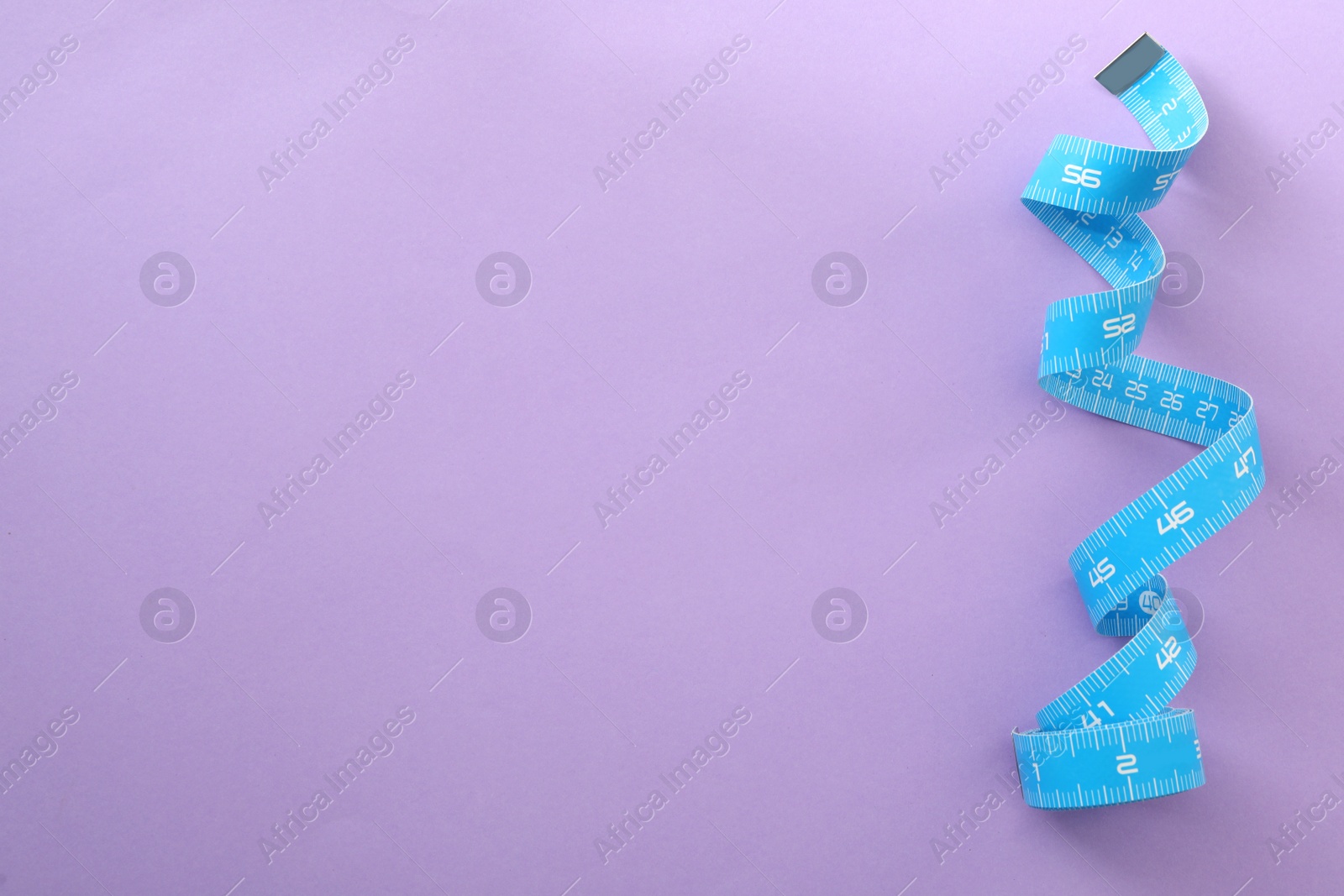 Photo of Light blue measuring tape on purple background, top view. Space for text