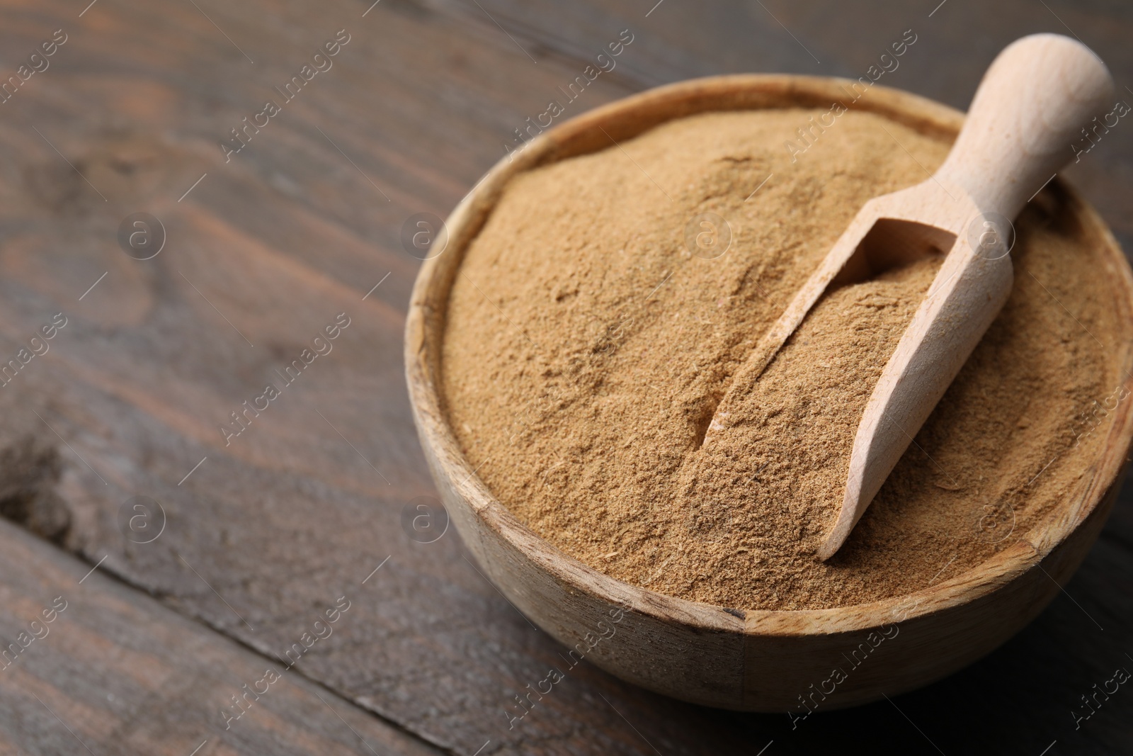 Photo of Dietary fiber. Psyllium husk powder in bowl and scoop on wooden table, closeup. Space for text