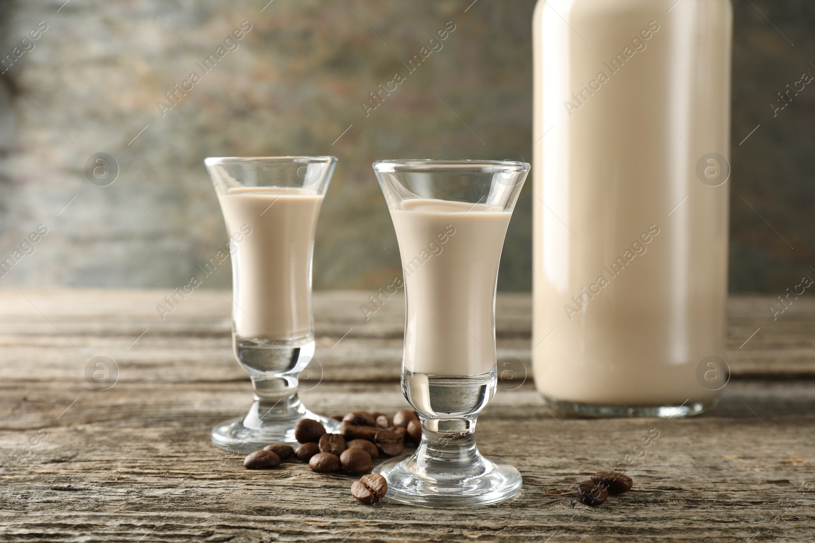 Photo of Coffee cream liqueur in glasses and beans on wooden table