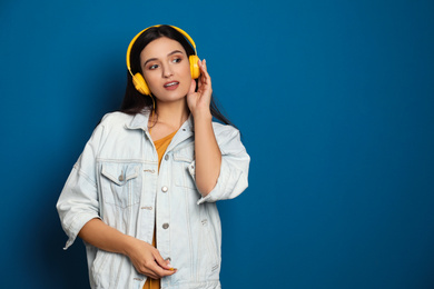 Photo of Young woman listening to audiobook on blue background. Space for text