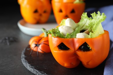 Photo of Bell pepper with black olives, mozzarella and lettuce as Halloween monster on dark table, closeup