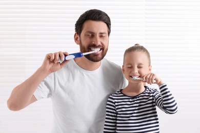 Father and his daughter brushing teeth together in bathroom