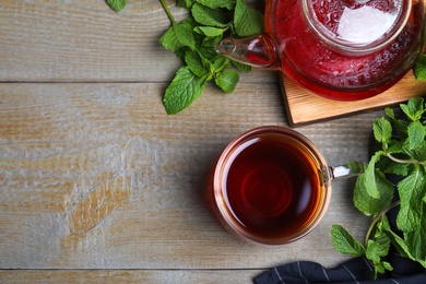 Photo of Flat lay composition with cup of hot aromatic mint tea on wooden table, space for text