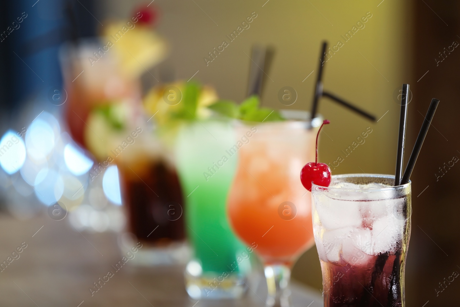 Photo of Row of different fresh alcoholic cocktails on bar counter