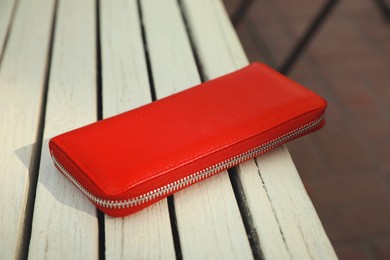 Photo of Red purse on wooden bench outdoors, closeup. Lost and found