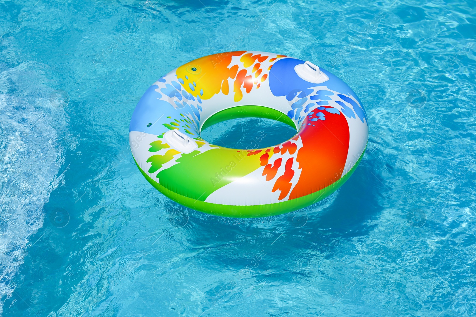 Photo of Colorful inflatable ring floating in swimming pool on sunny day