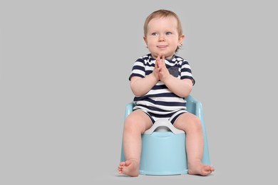 Photo of Little child sitting on baby potty against light grey background, space for text