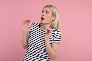 Portrait of surprised woman on pink background