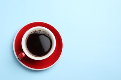 Photo of Aromatic coffee in cup on light blue background, top view. Space for text