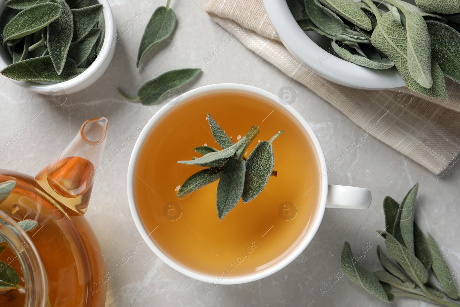 Photo of Flat lay composition with cup of sage tea and green leaves on light grey table