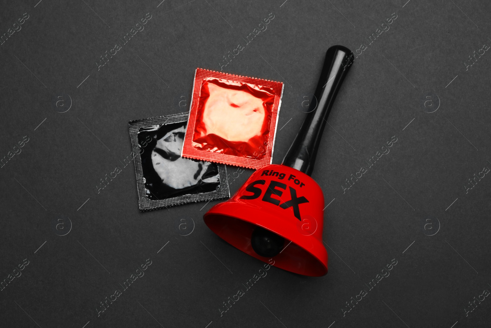 Photo of Sex bell and condoms on black background, top view