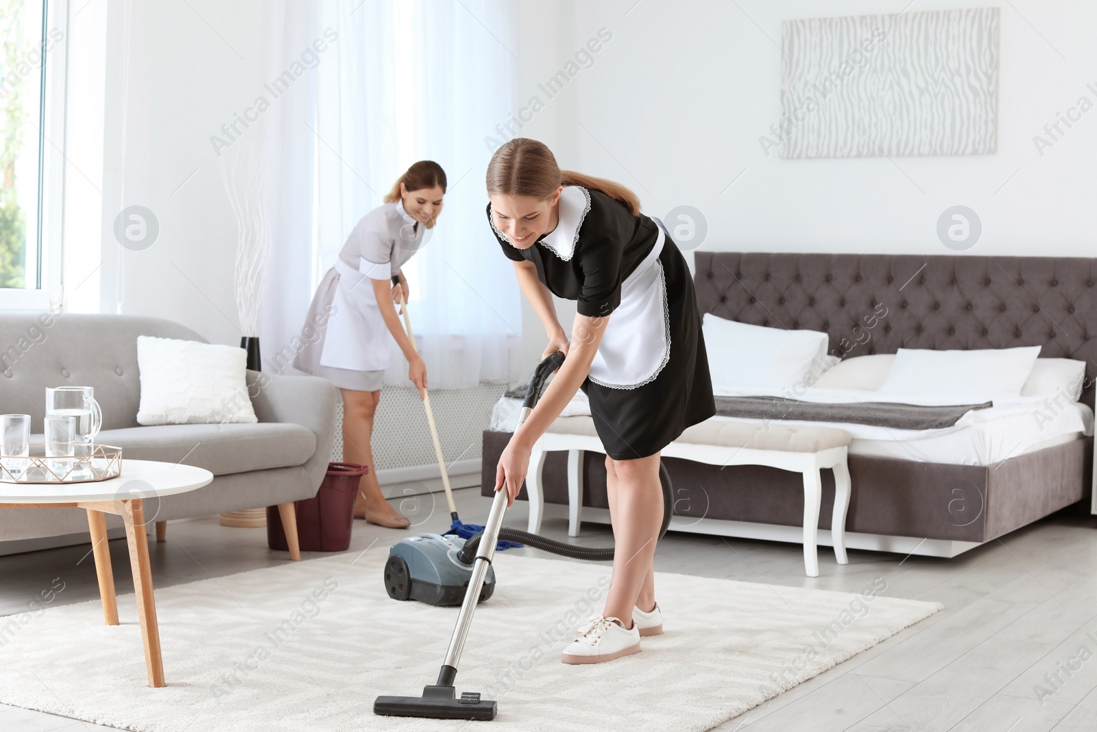 Photo of Professional chambermaids cleaning floor in hotel room