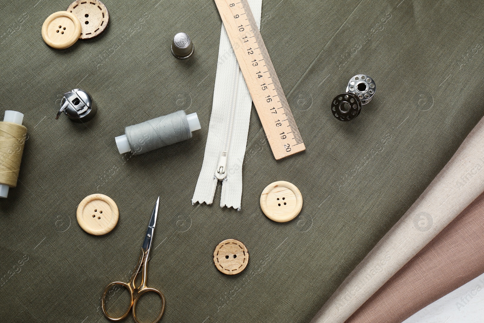 Photo of Different sewing supplies and accessories on fabric, flat lay