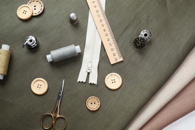 Photo of Different sewing supplies and accessories on fabric, flat lay