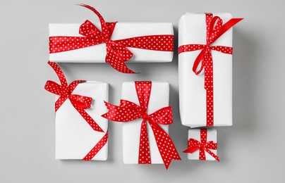 Christmas gift boxes with red bows on grey background, flat lay