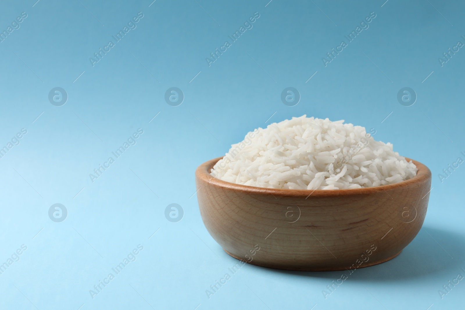 Photo of Bowl of tasty cooked rice on color background. Space for text