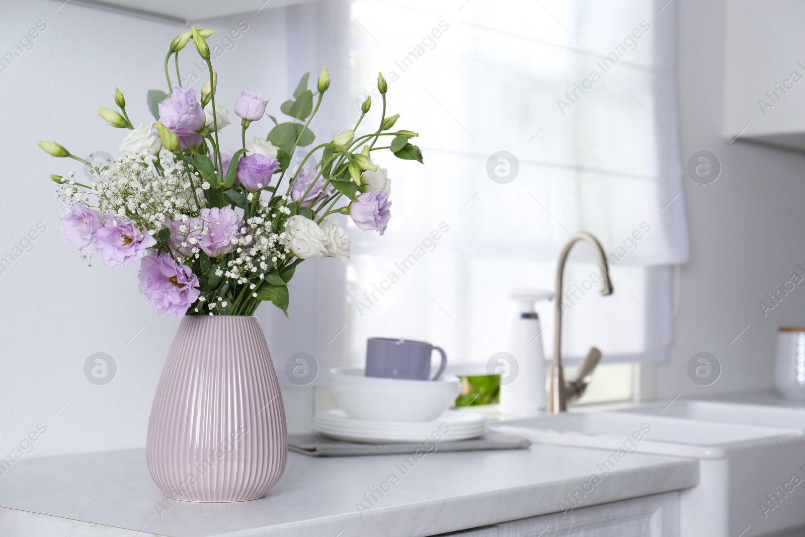 Photo of Beautiful bouquet with Eustoma flowers on countertop in kitchen. Space for text