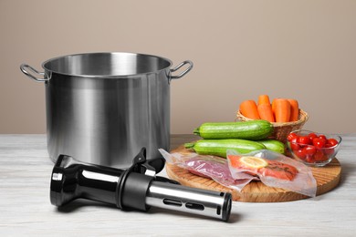 Photo of Thermal immersion circulator, ingredients and pot on white wooden table. Vacuum packing for sous vide cooking
